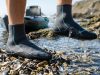 : Person wearing durable neoprene water socks walking on a rocky riverbed.
