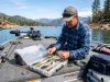 Angler organizing tackle gear inside a storage box on a California boat.