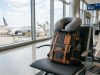 Travel neck pillow attached to a backpack in an airport terminal.