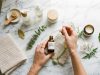 Person organizing minimalist skincare products on a marble vanity in natural morning light.